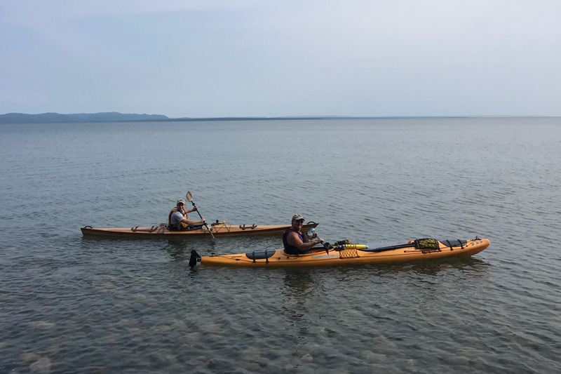 two kayakers paddling close together near shore