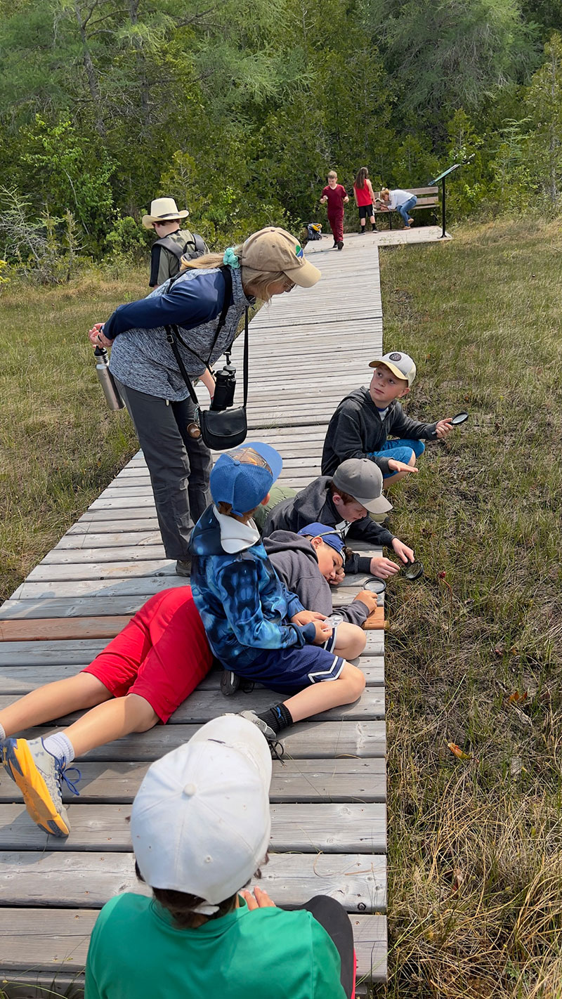 group of children on a boardwalk learning about pitcher plants